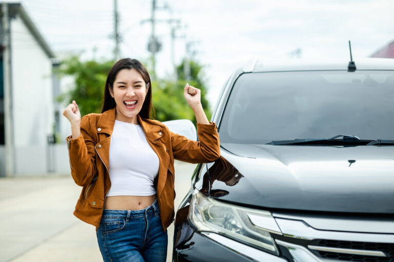 mulher comemorando ao lado de um carro